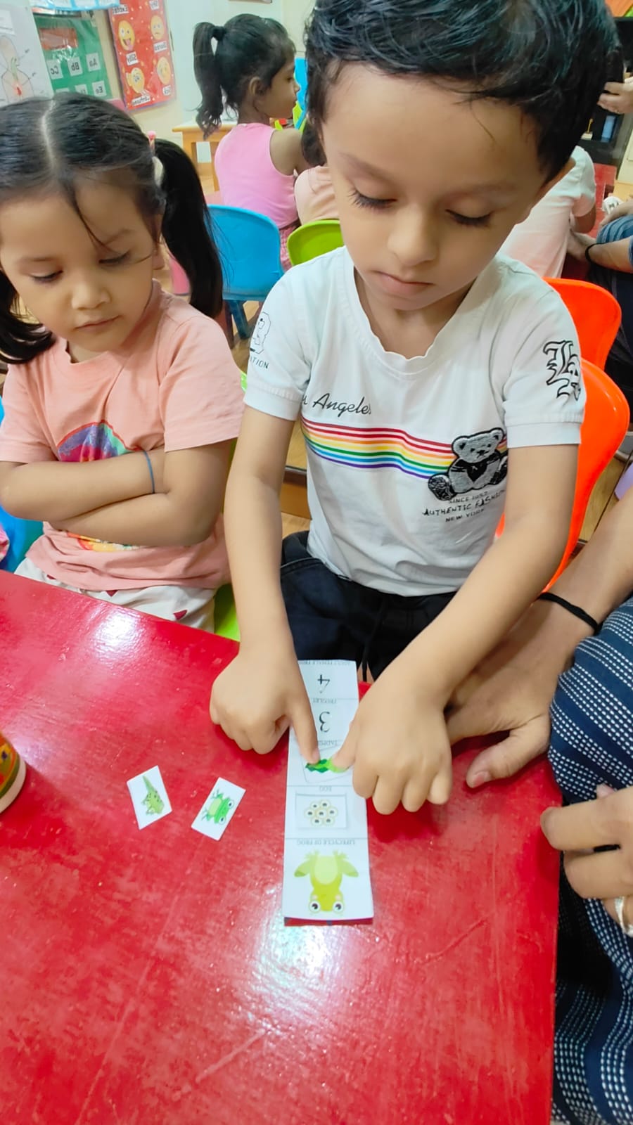 Children exploring a frog lifecycle activity at a table